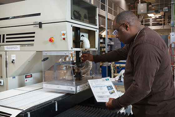 A warehouse worker uses approved LOTO procedures to ensure compliance while performing required maintenance on a piece of industrial equipment.
