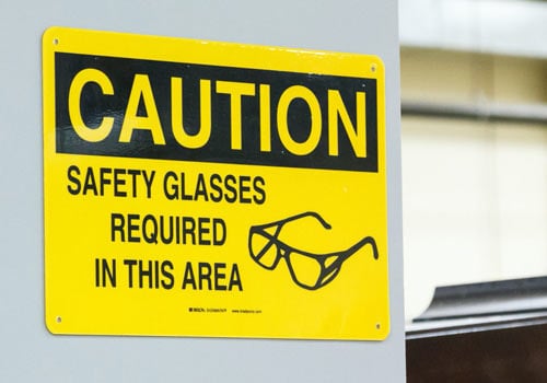 Sign that reads &quot;Caution, safety glasses required in this area&quot;