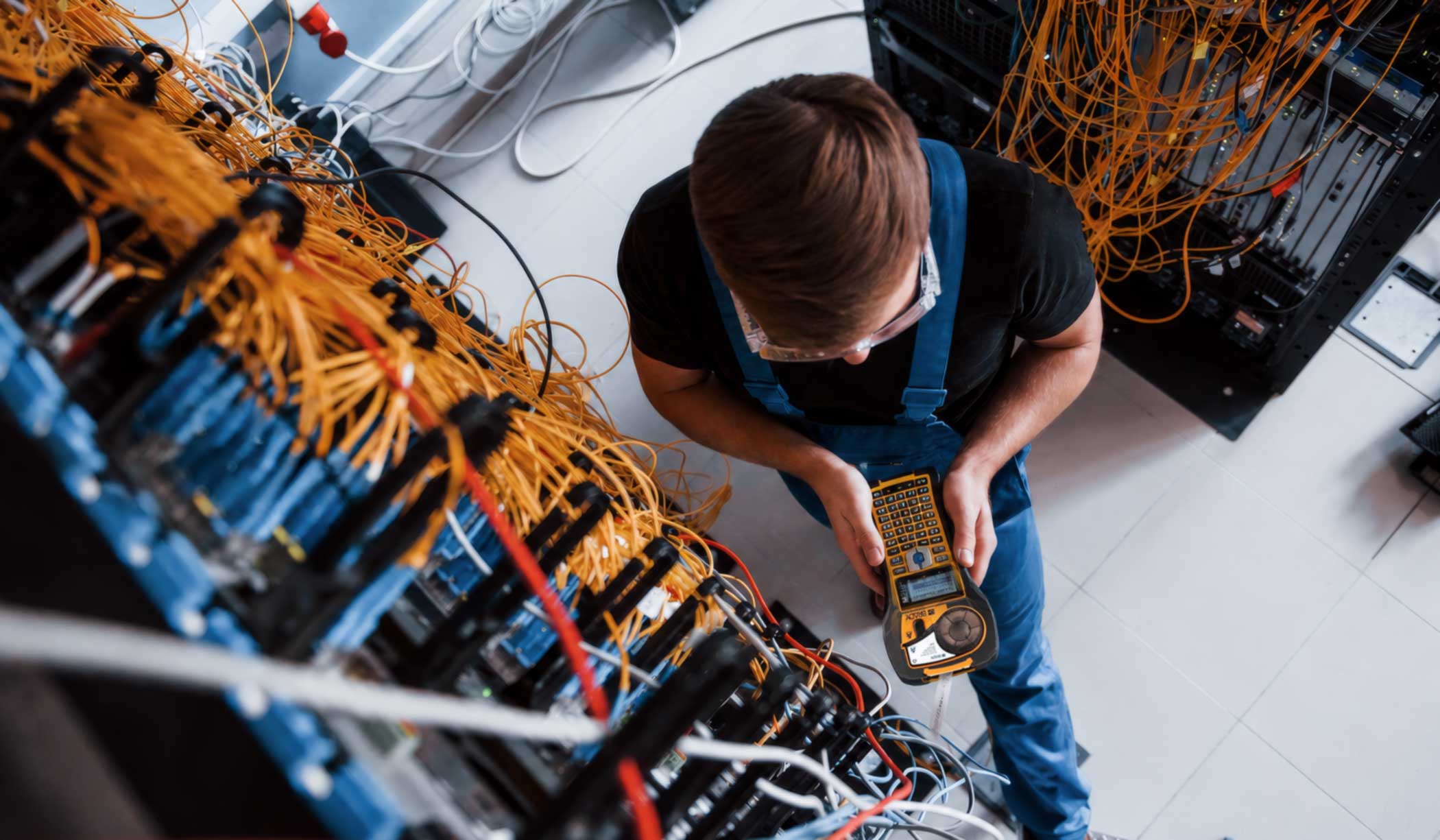 An electrician labels wires on a server rack using an M210 Label Printer