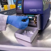 Gloved hands touching a Brady i7100 industrial label printer.