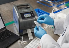 A lab tech prints labels on a printer.  