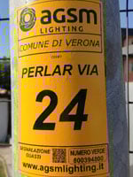 Yellow Brady B-595 label on pole outdoors.