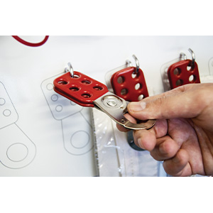 Hand removing a red group lockout hasp from a white shadow board. 