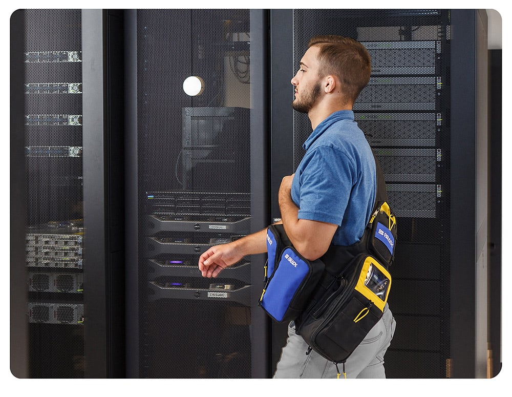 Maintenance tech walking with a Brady M611 strapped around shoulder.