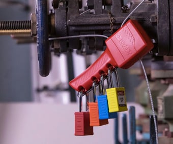 A collection of colored locks attached to a group lockout hasp on a lockout device.