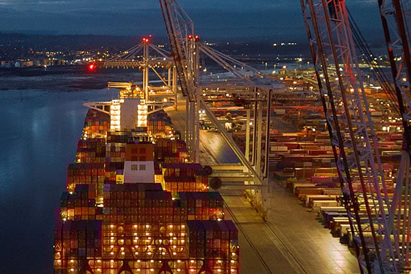 Large container ship docked at a dry dock at night.