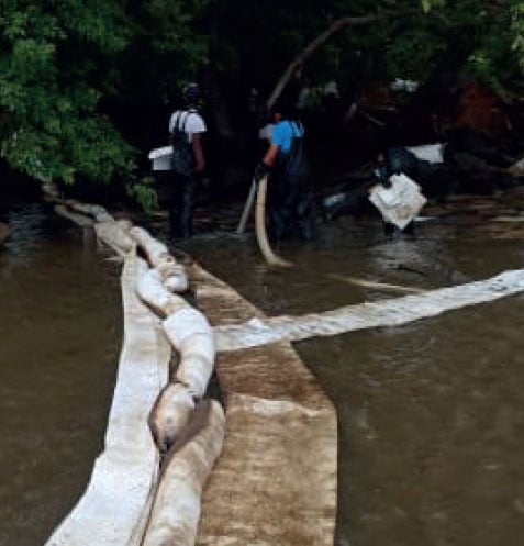 Workers clean up an oil spill in body of water.
