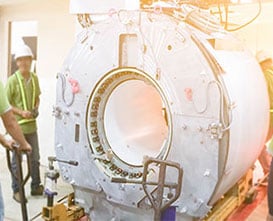 A worker wearing PPE standing next to a large piece of equipment.