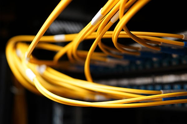 Yellow fiber optic cables connected to network equipment. 