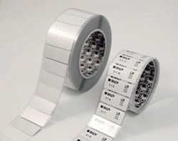 A roll of blank labels next to a roll of printed labels.