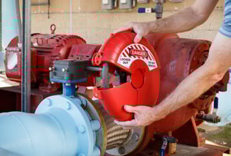 Worker installs a red, circular LOTO device on a valve.