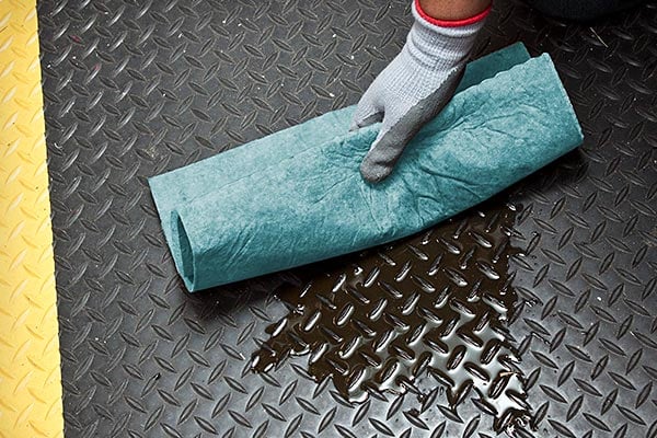 Person soaking up liquid on the ground with a cloth.