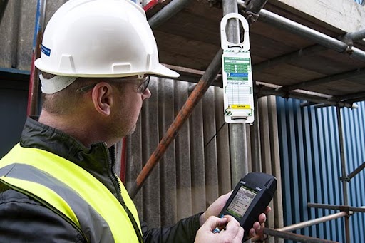 Worker in hardhat inspecting a tag.