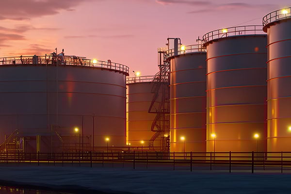 Cylindrical storage tankers likely holding oil at sunset or sunrise. 