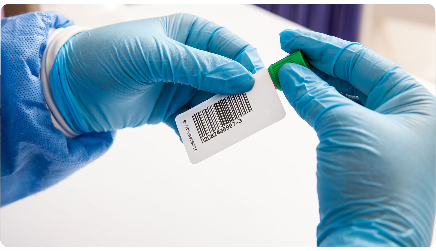 Person in blue medical gloves holding and inspecting a small prescription bottle or vial