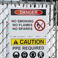 A danger and a caution safety sign mounted to a chain link fence.