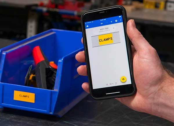A label design on an Express Labels Mobile screen next to the actual printed label. Both are a vivid yellow and say “CLAMPS”.