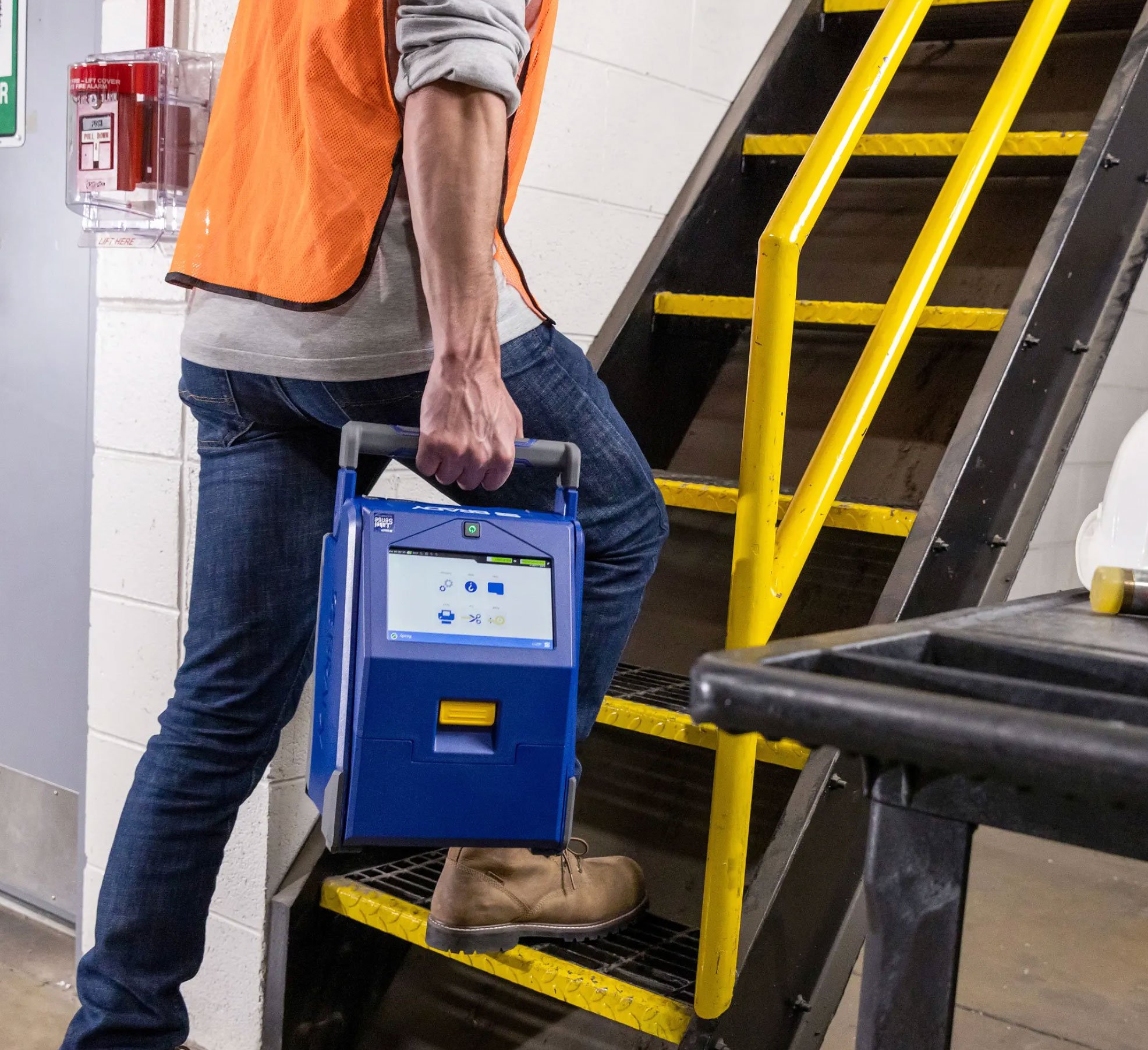 Worker carrying the portable Brady i4311 up a flight of stairs