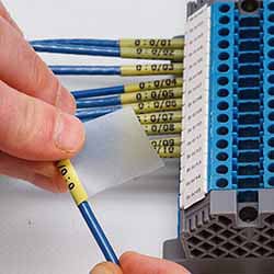 A pair of hands applying a wire cable label to a wire