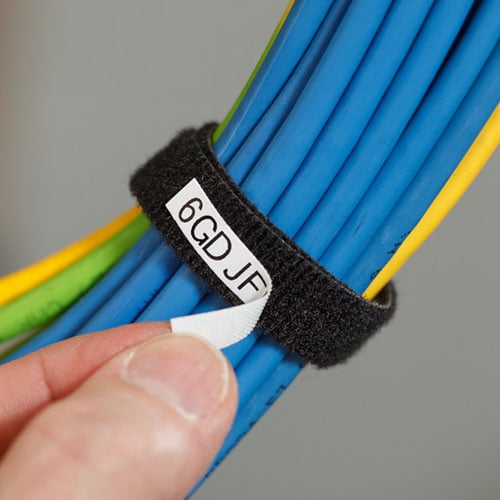 A hand peeling a label off a group of wires