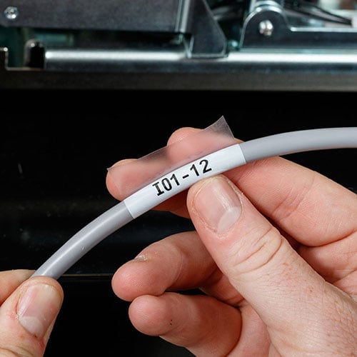 A hand wrapping a label around a wire