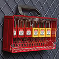 A wall-mounted Brady group lock box with yellow and red padlocks.