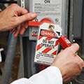 Person applying a lockout padlock and a "Do Not Operate" tag.