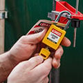 Person applying a yellow Brady lockout padlock.