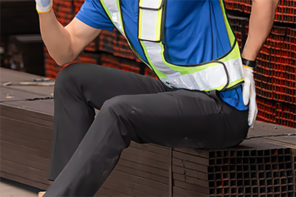A man sitting and holding his back in pain.