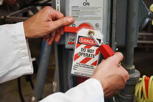 A person applying a lockout padlock and tag to prevent accidental energization.