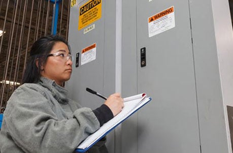 an electrical worker taking notes at an electrical panel