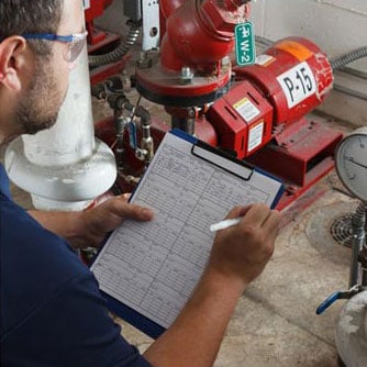 a tech with a checklist inspecting a industrial pump
