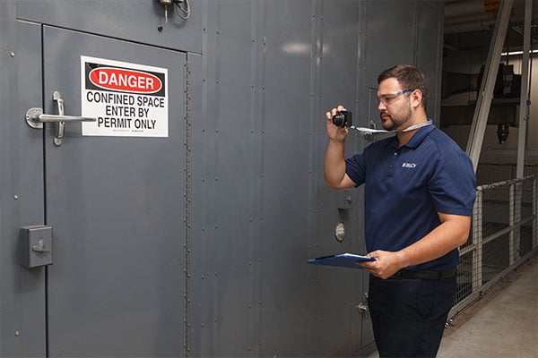 A tech taking a photo of a sign labeled confined space