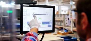 Worker monitors an industrial process with a touchscreen. 