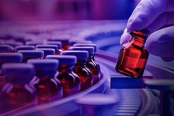 Closeup image of pharmaceutical vials on a conveyor belt. 