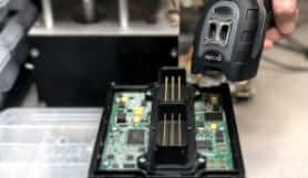 Handheld Brady barcode scanner scans an open circuit board. 