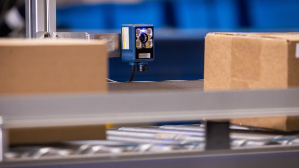 Brady fixed scanner scanning cardboard boxes on a conveyor belt.