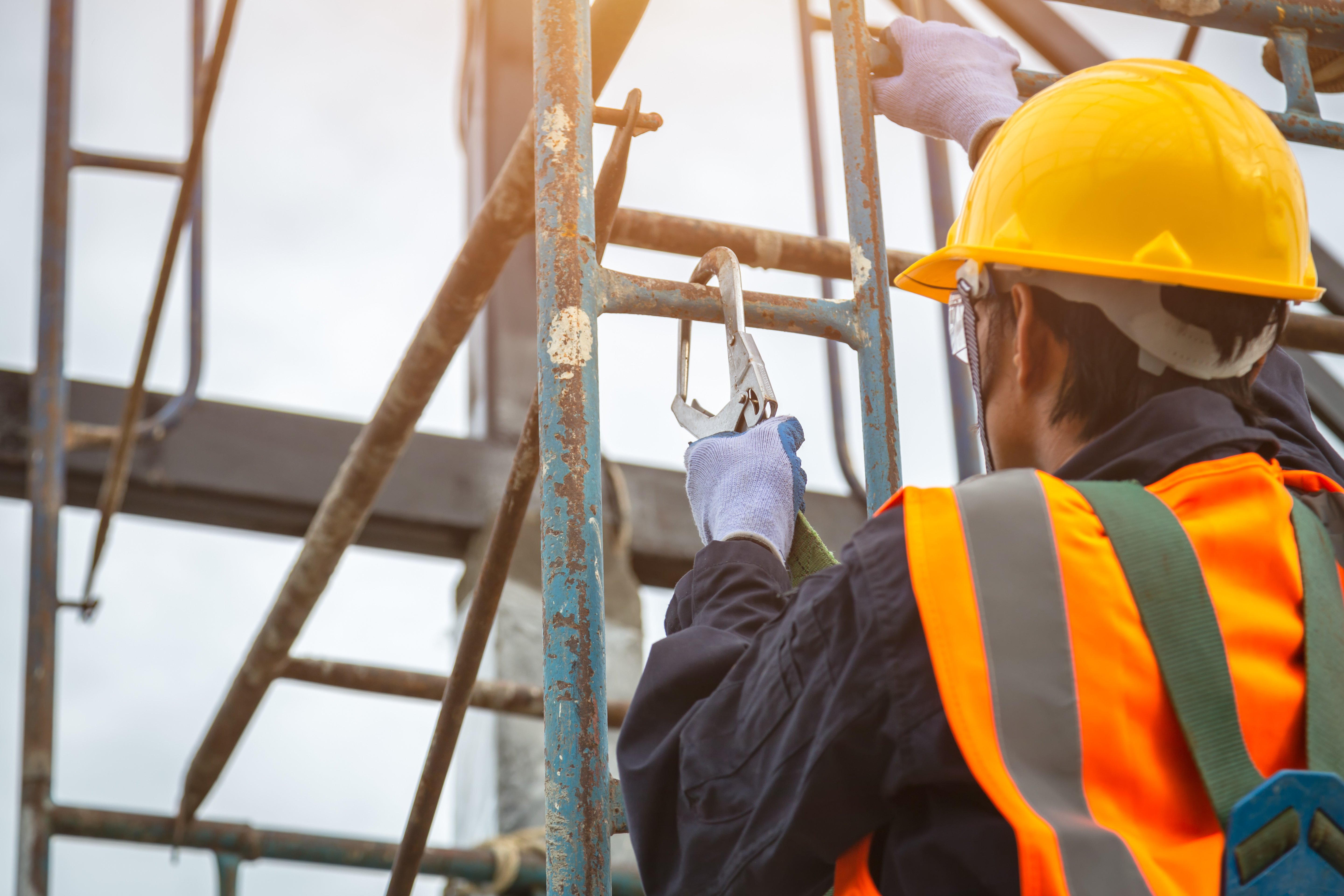 Construction worker attaching fall protection.