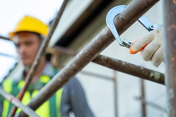 Construction workers hooking fall protection to scaffolding.