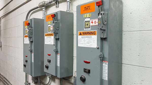 Three electrical boxes with disconnect switches/panels and warning labels.