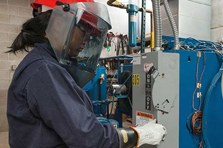 Worker in PPE investigates electrical breaker box. 