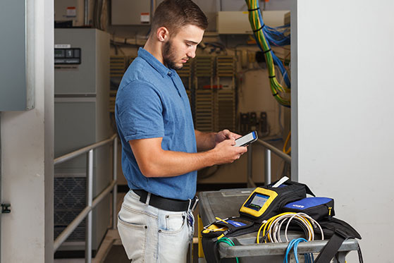 A worker using a mobile app and printer to create wire markers in a data center.