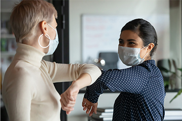 Two employees bumping elbows during COVID.