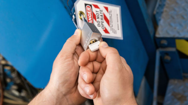 Worker applying a safety padlock to lock out machinery. 