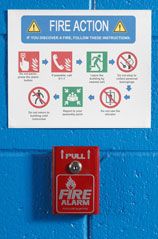 Wall mounted fire safety instructions and fire alarm.