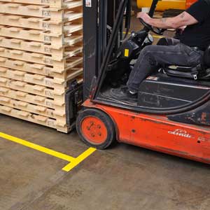 Forklift and pallets with yellow floor marking tape.