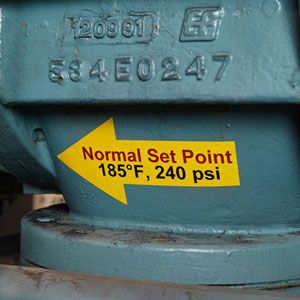 Industrial equipment with yellow temperature and pressure label.
