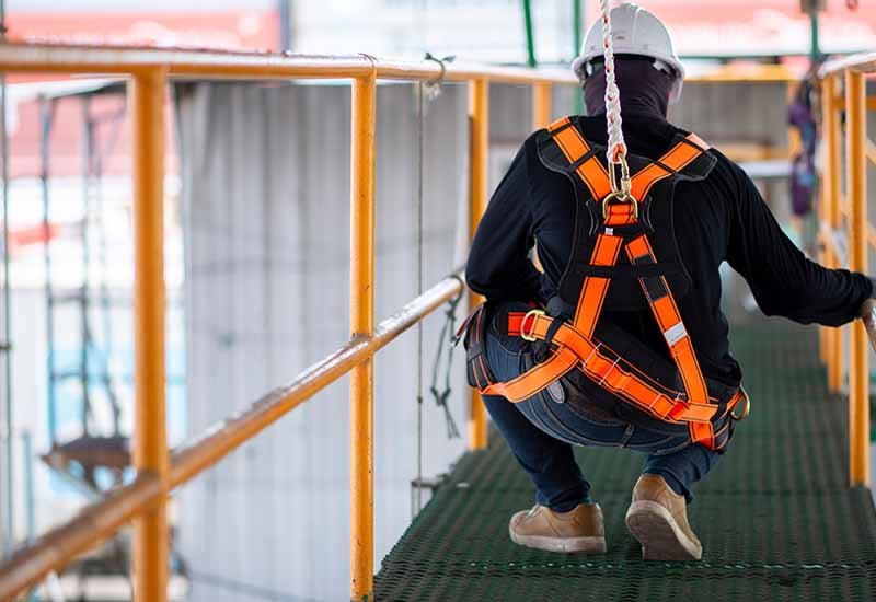 Man in safety harness on walkway.