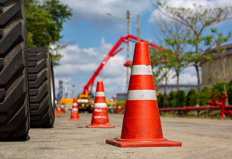 Traffic cone next to heavy equipment tire