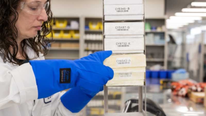 Woman holding box with labels in a lab.  